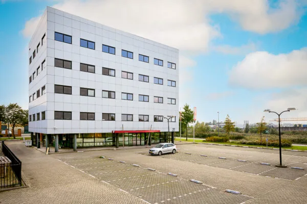 Modern kantoorgebouw aan de Karel Doormanweg met een deels lege parkeerplaats op de voorgrond.